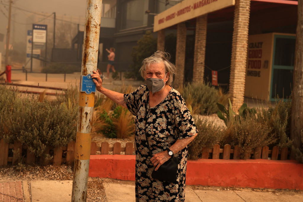 ATHENS, GREECE - AUGUST 12: A woman wears a mask to protect herself from the smoke, during a wildfire in Nea Penteli near Athens, Greece, on August 12, 2024. (Photo by Costas Baltas/Anadolu via Getty Images)